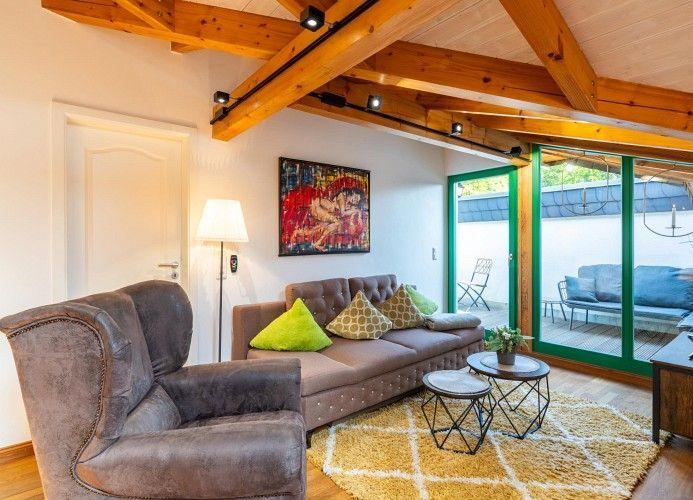 Wohnzimmer mit Sofa, Sessel und Glasfront zur Terrasse.