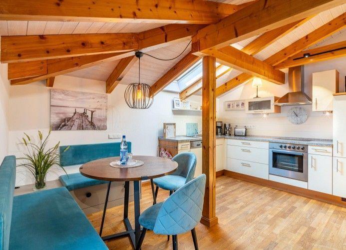 Essbereich mit runder Tisch und blauen Stühlen unter Holzbalkendecke