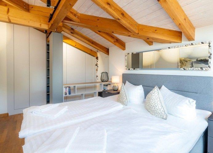 Schlafzimmer mit Doppelbett, Holzdecke und Kleiderschrank.