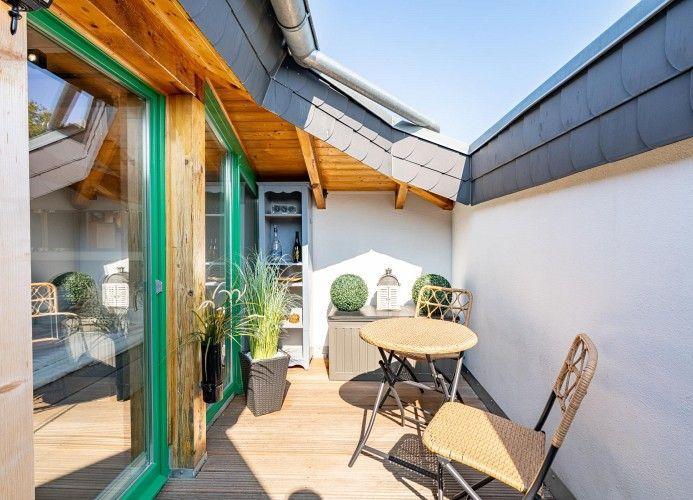 Terrasse mit Tisch, Stühlen und Pflanzen unter Dach
