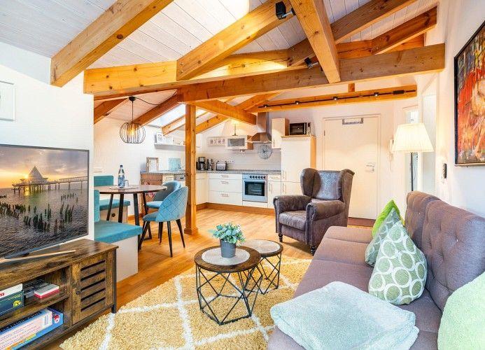 Wohnbereich mit Sofa, Couchtisch und Fernseher unter Holzbalkendecke