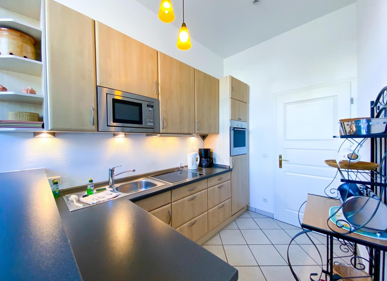 Küche mit Holzschränken, Mikrowelle, Kühlschrank und Arbeitsplatte.