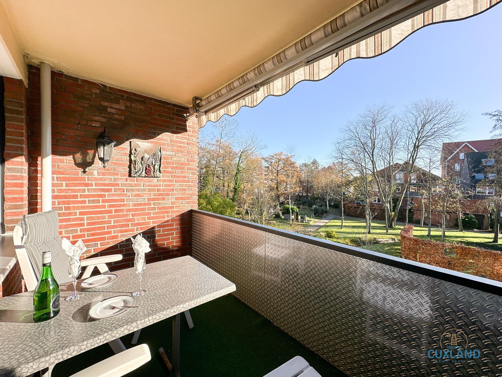 Terrasse mit Tisch, Stühlen und Blick auf Garten und Häuser.