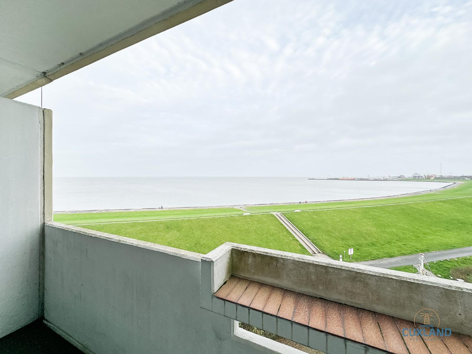 Terrasse mit Blick auf Grünflächen und Meer.