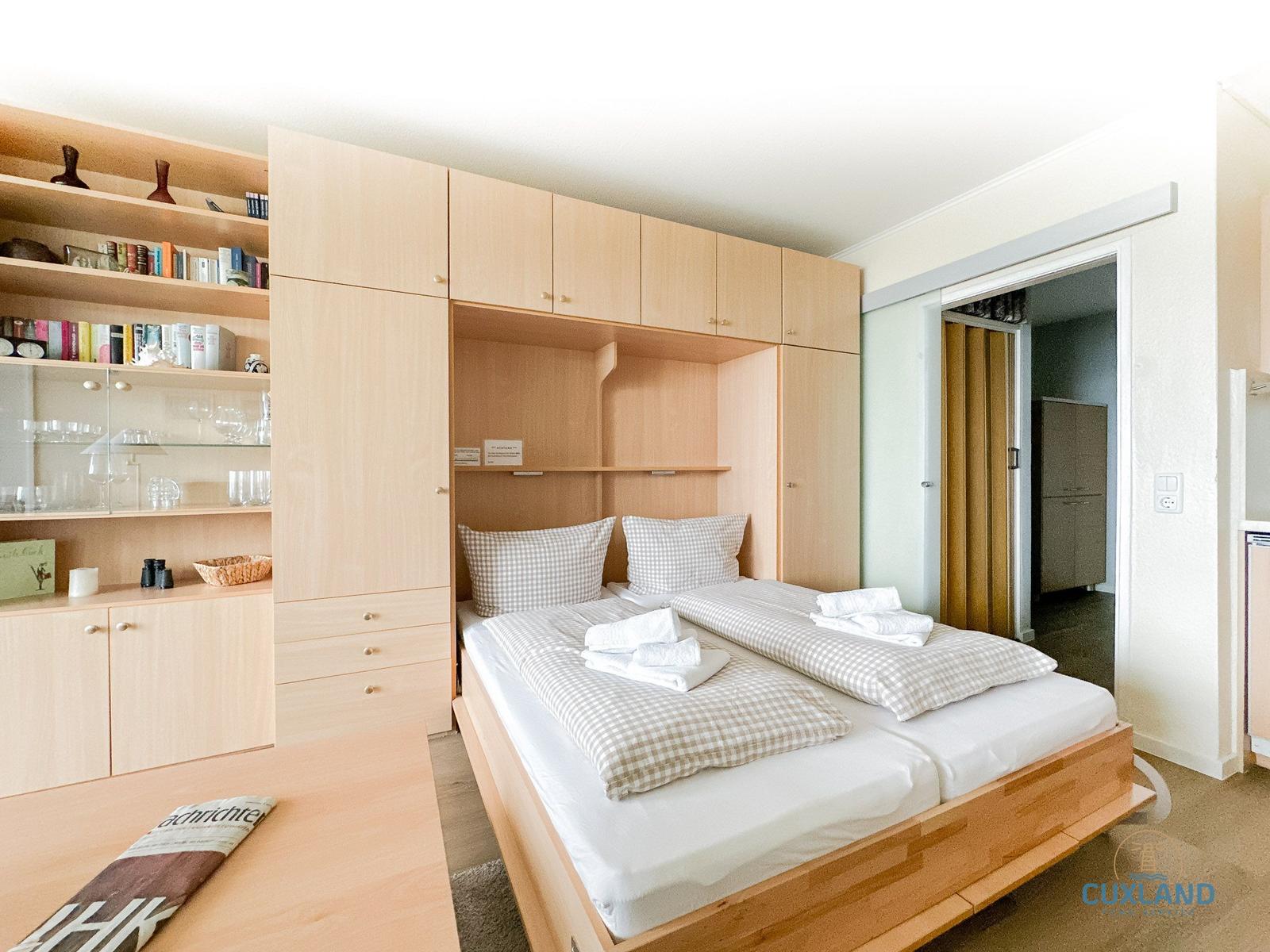 Schlafzimmer mit Doppelbett, integriertem Schrank und Bücherregal.