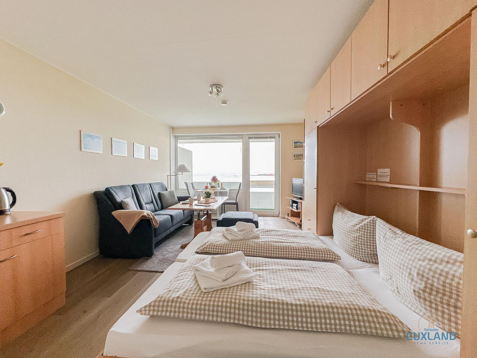 Zimmer mit Schlafplatz, Sofa, Tisch und Balkon mit Meerblick.