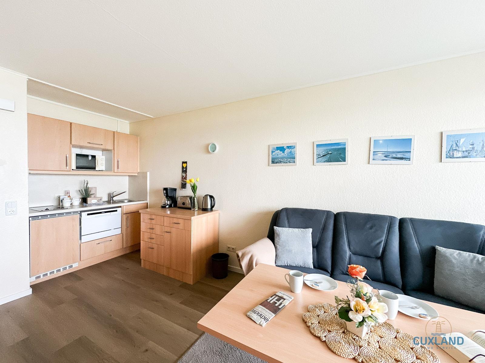 Wohn- und Küchenbereich mit Sofa, Tisch und Küchenschränken.