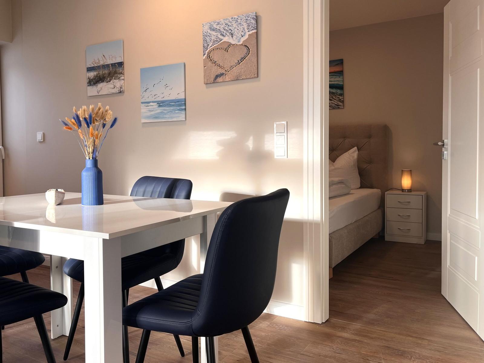 Essbereich mit Tisch und Stühlen, Schlafzimmer mit Bett und Nachttisch sichtbar.