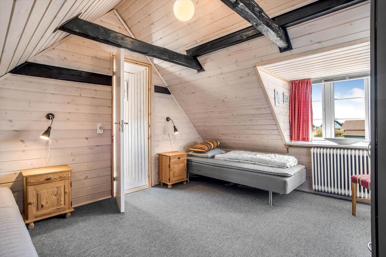 Bedroom with wooden walls, bed, nightstand, and window with view.