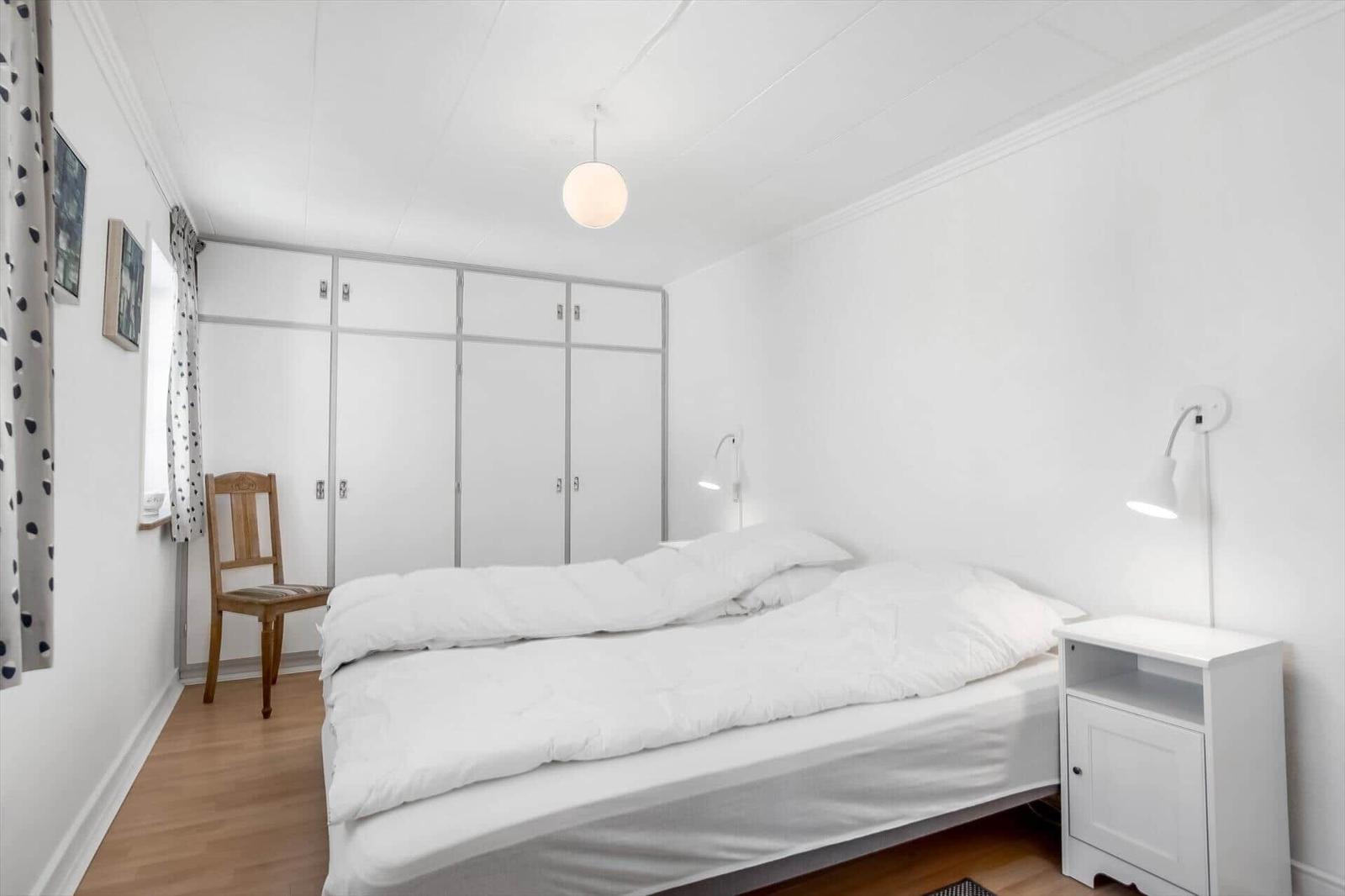 Bedroom with bed, nightstand, wardrobe, and chair.
