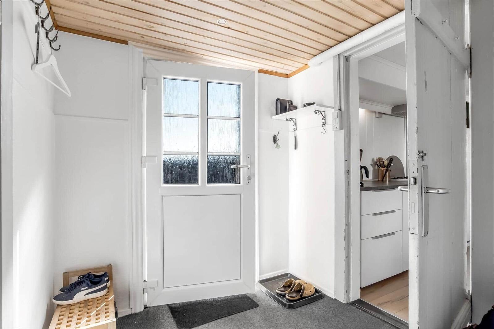 Entrance with door, shoes, and view into the kitchen.