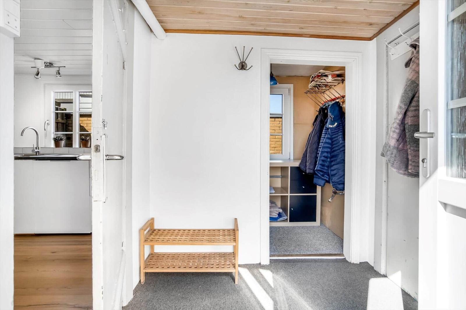 Entrance area with closet, wooden bench, and view into kitchen and bedroom.