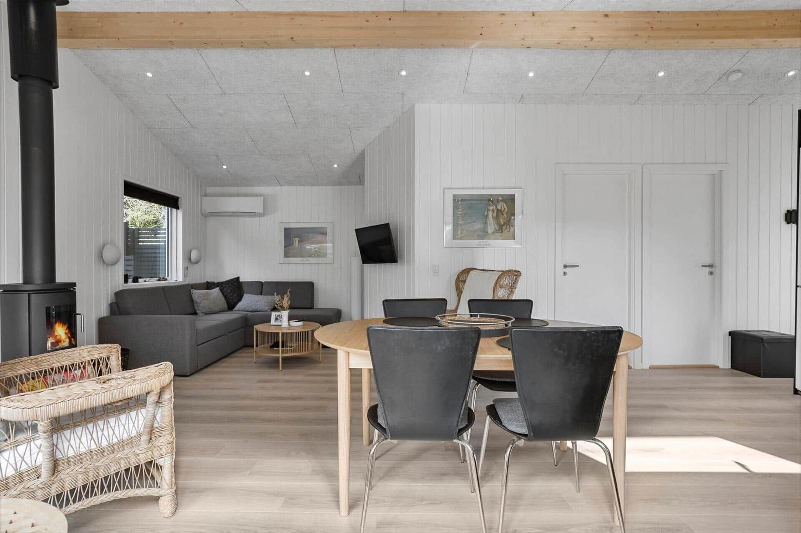 Living and dining area with sofa, dining table, and wood stove.
