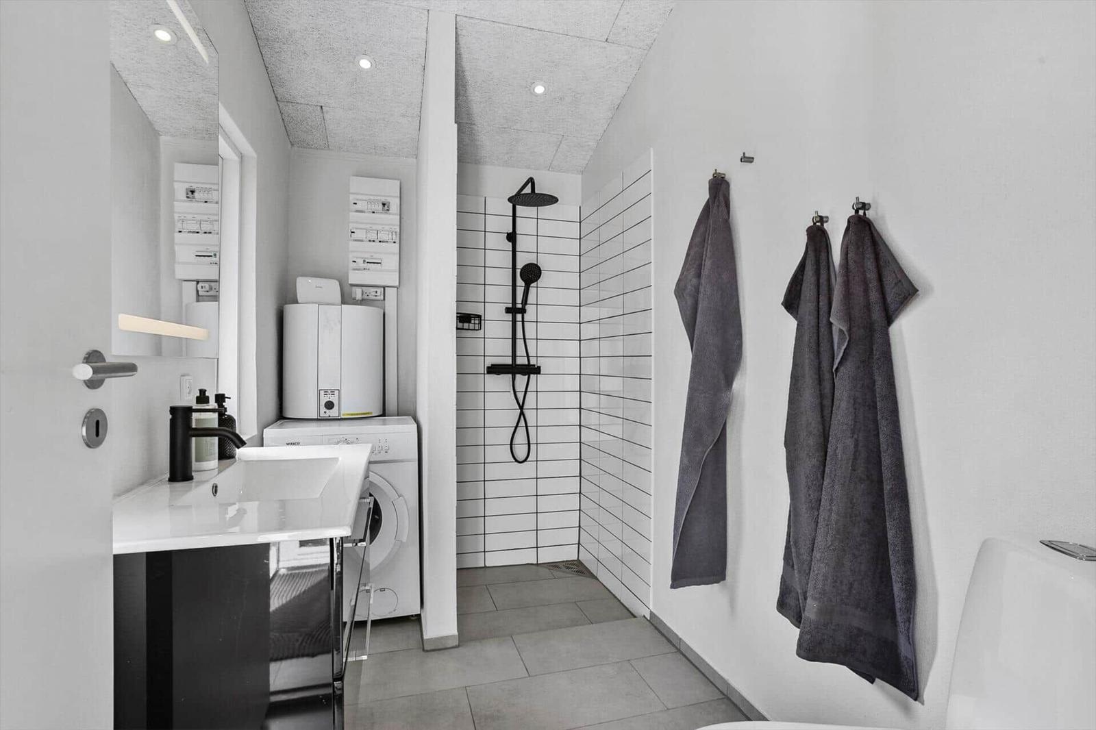 Bathroom with shower, washing machine, and towels on the wall.