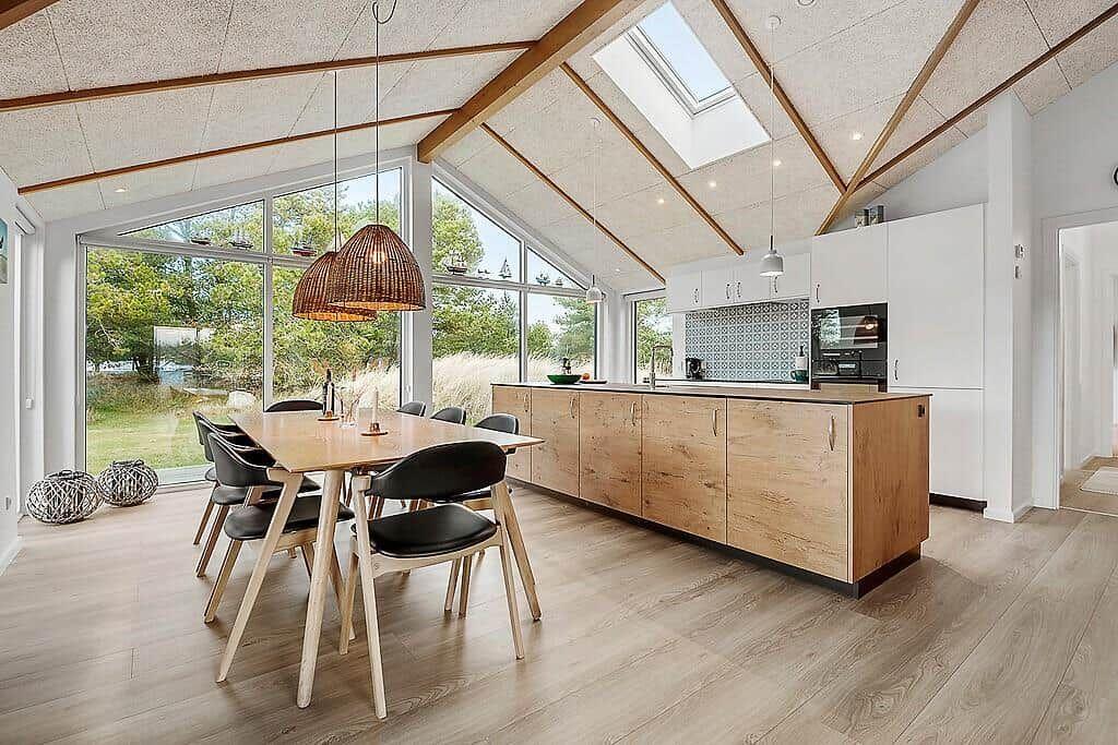 Kitchen and dining area with wooden surfaces and large windows for outdoor views.