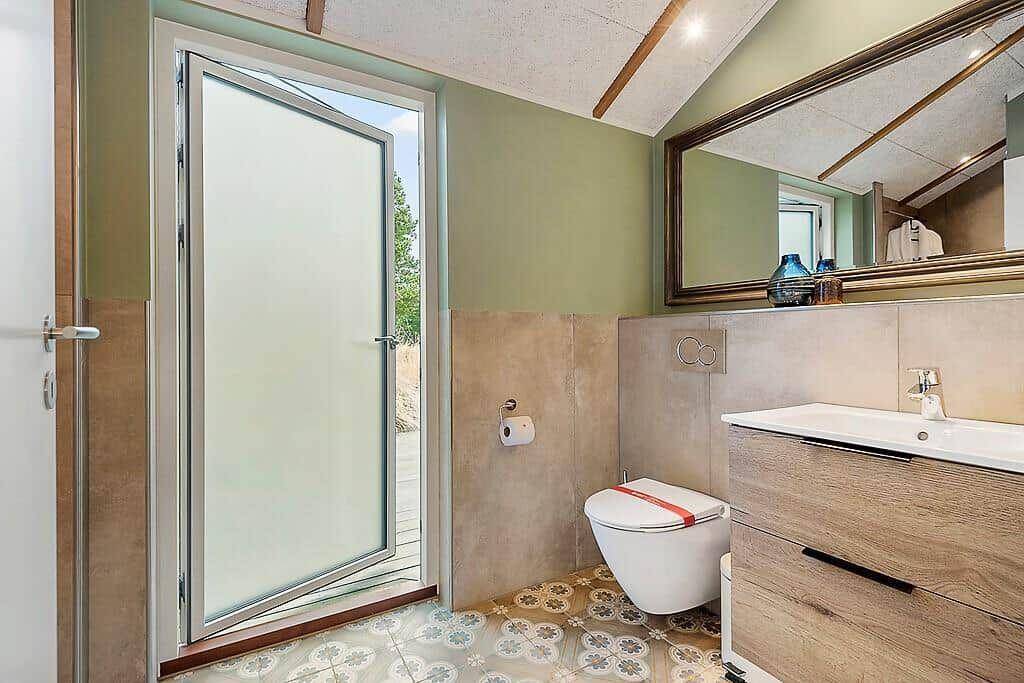 Bathroom with toilet, sink, and glass door to terrace.