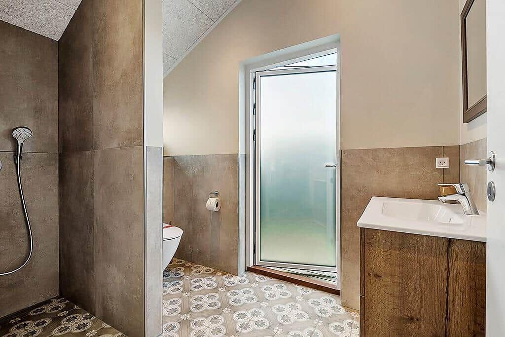 Bathroom with shower, toilet, and sink with wooden vanity.