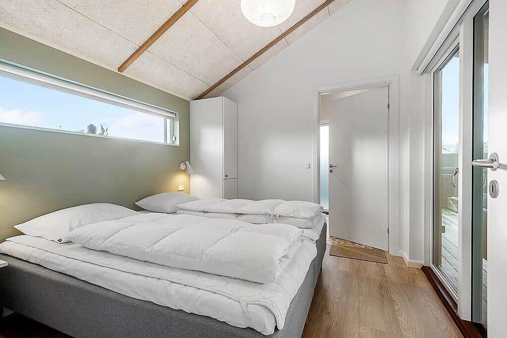 Bedroom with double bed, wooden floor, and large window. Door leads to balcony.