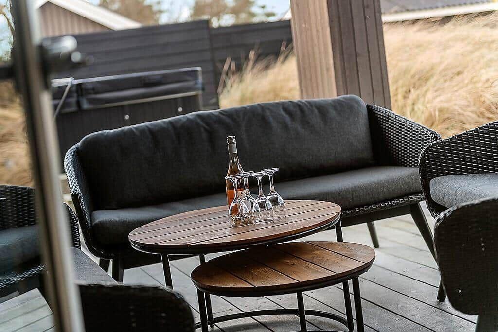 Deck with seating group, table, and wine bottle in background.