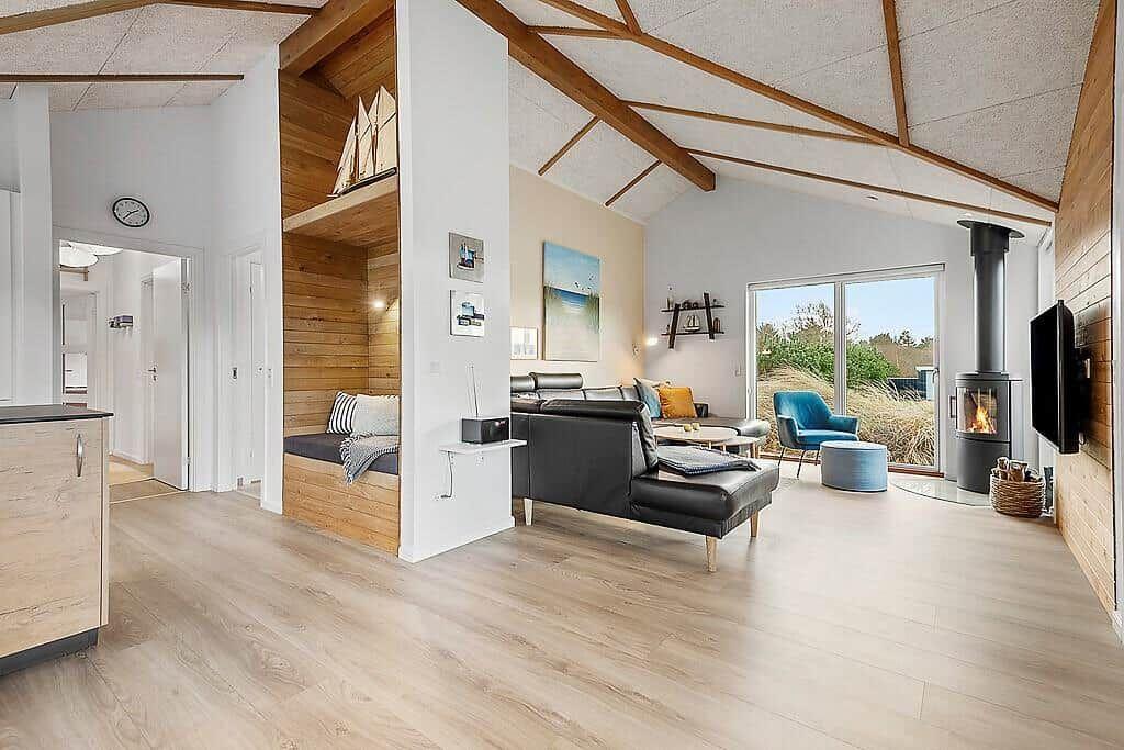 Living area with wooden ceiling, sofa, fireplace, and view of greenery.