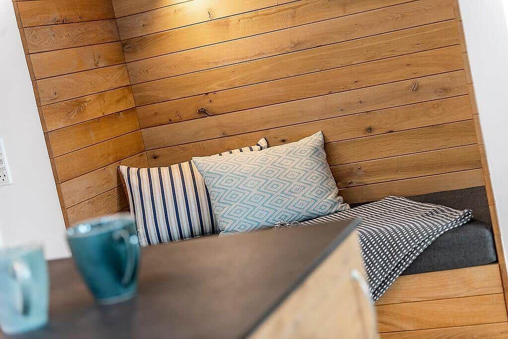 Corner bench with cushions and blanket against wood-paneled wall