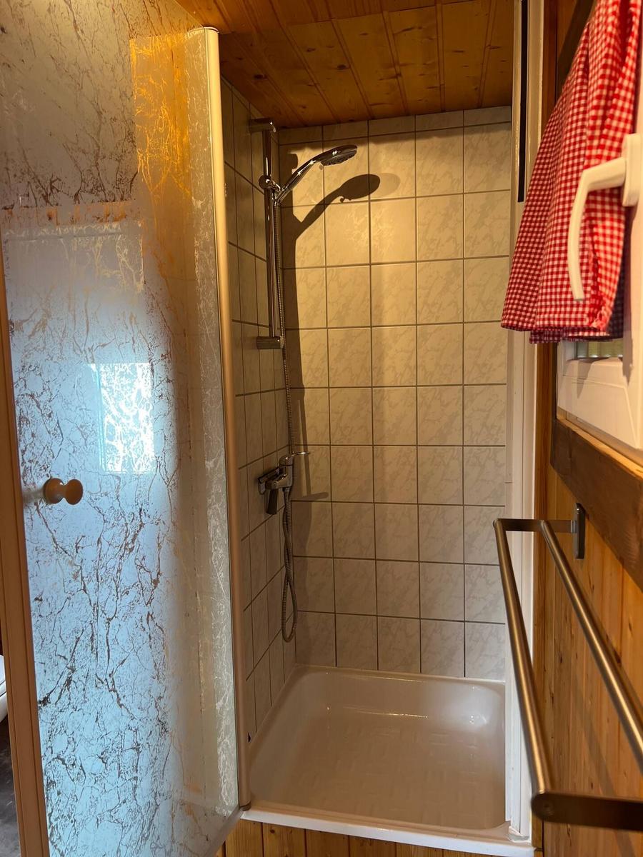 Dusche mit Duschbrause und Glaswand in Holzbad