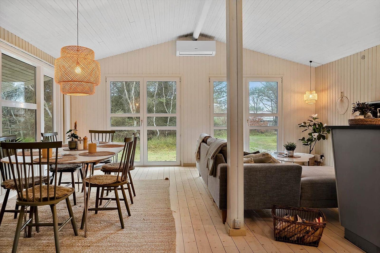 Essbereich mit Tisch und Stühlen, Wohnbereich mit Sofa und Fenstern zum Garten.