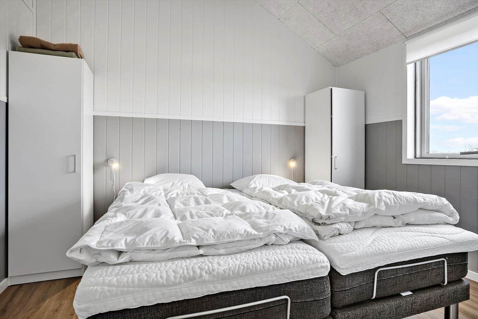 Schlafzimmer mit Doppelbett, weißen Kissen und Kleiderschränken an den Wänden.
