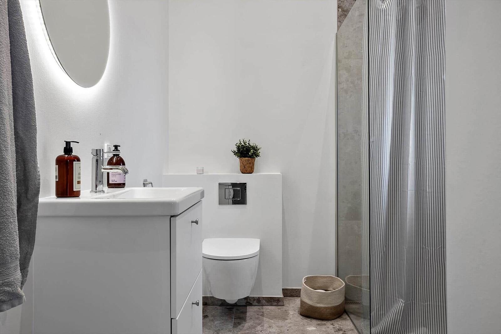 Badezimmer mit Waschbecken, Toilette und Dusche mit Streifenvorhang.