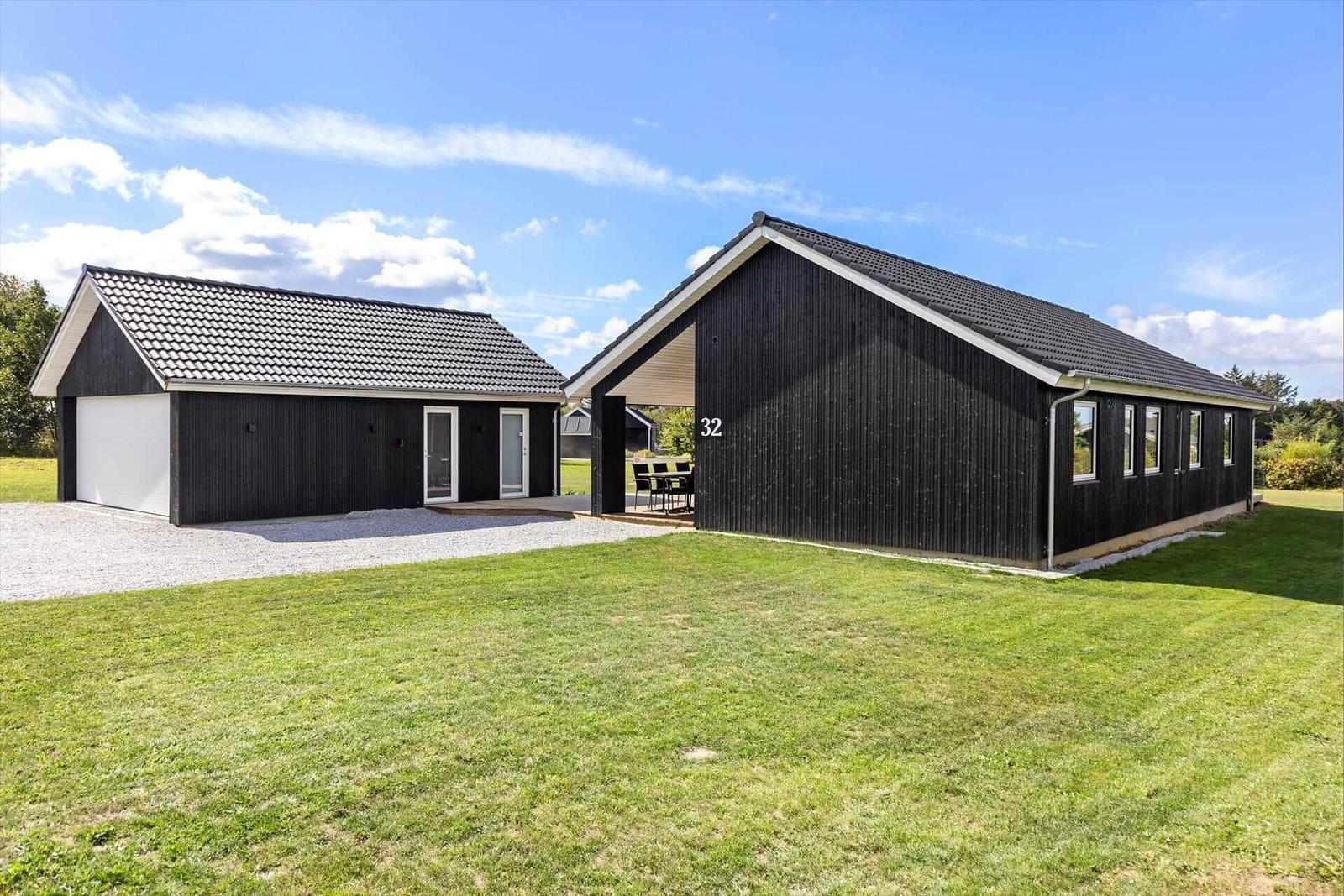 Moderne Holzhäuser mit Garten und Terrasse unter blauem Himmel.