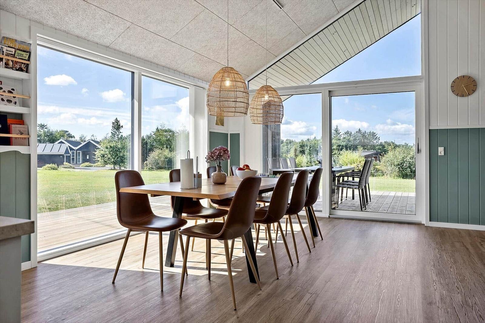 Essbereich mit Tisch, Stühlen und großen Fenstern zum Garten.