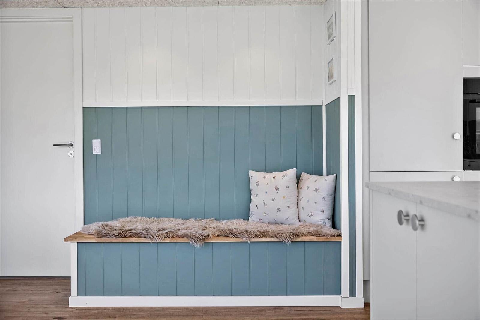Sitzbank mit Felldecke und Kissen an blauer Wand