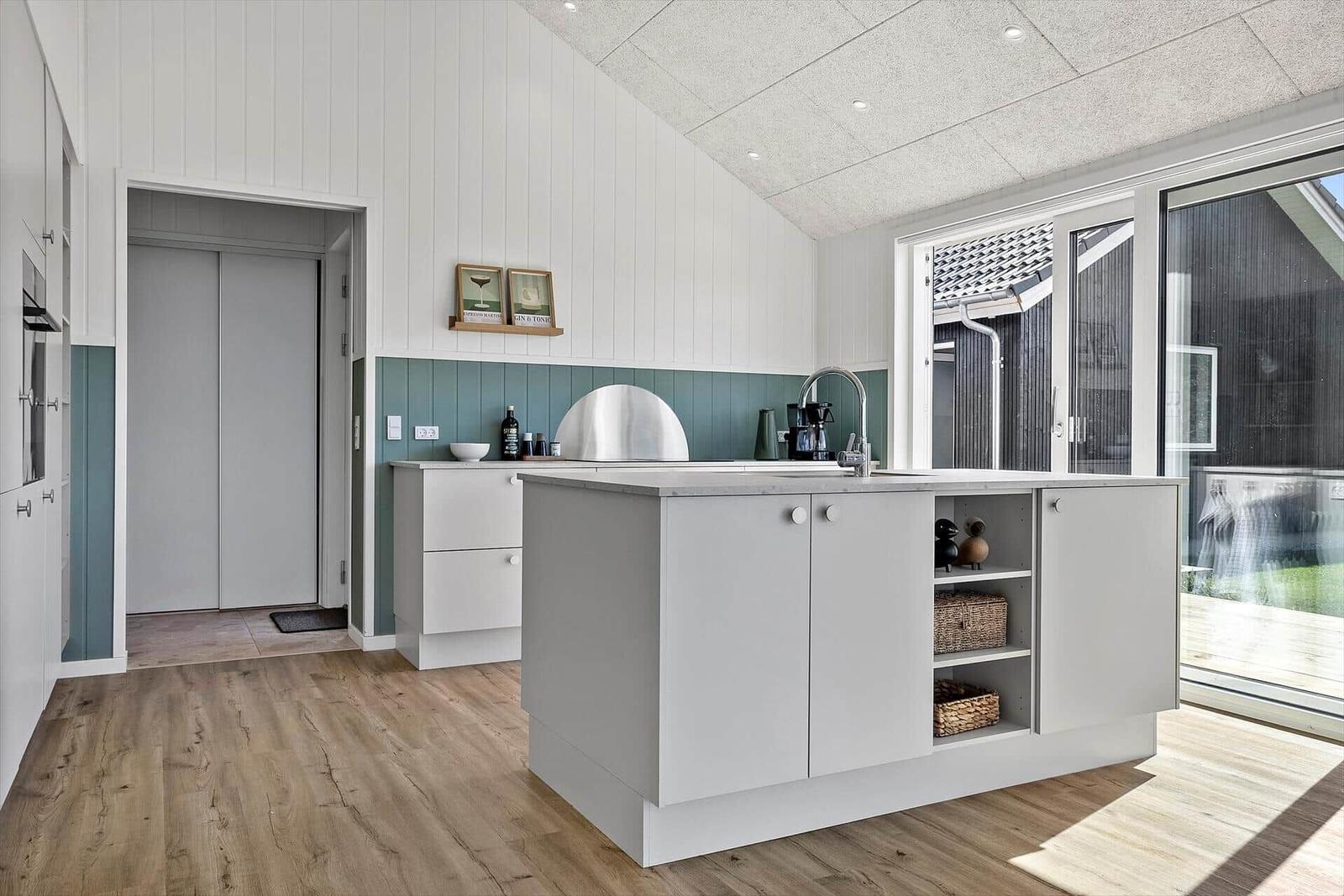 Moderne Küche mit Kücheninsel, Holzboden und großem Fenster.