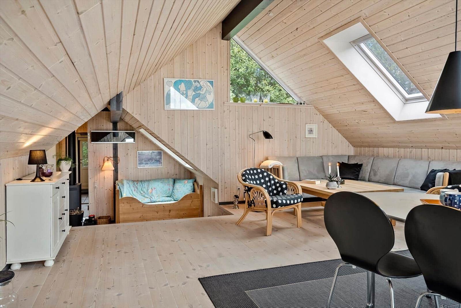 Wohnraum mit Holzwand, Schlafcouch und Dachschrägenfenstern.