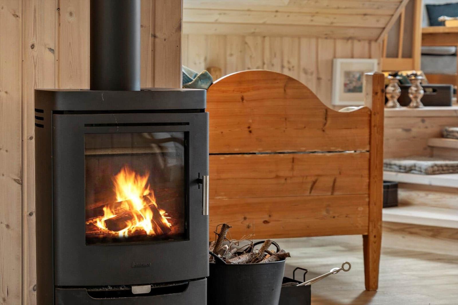 Holzofen mit brennendem Feuer neben einem Holzbett.