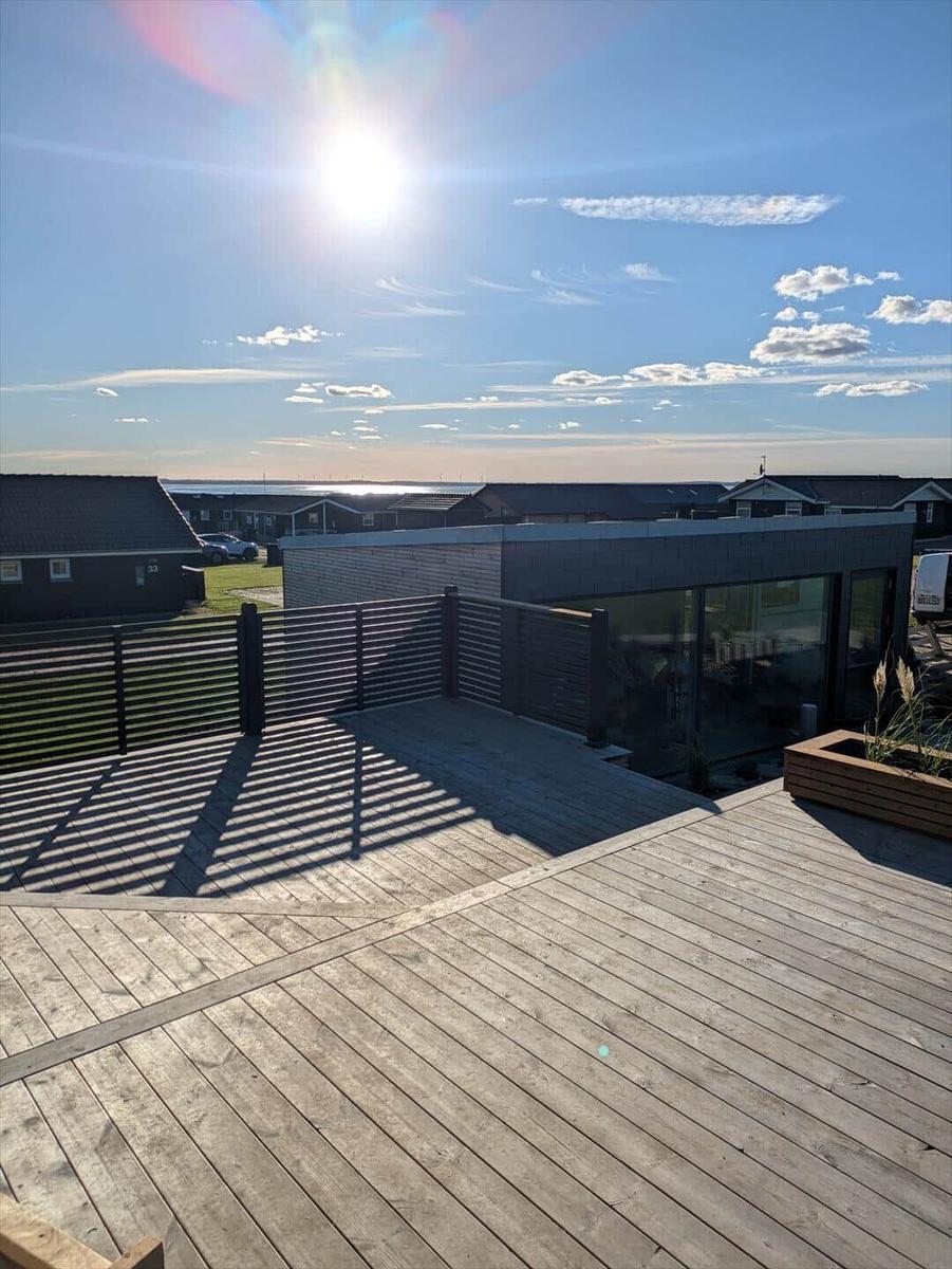 Holzterrasse mit Blick auf das Meer und moderne Häuser.