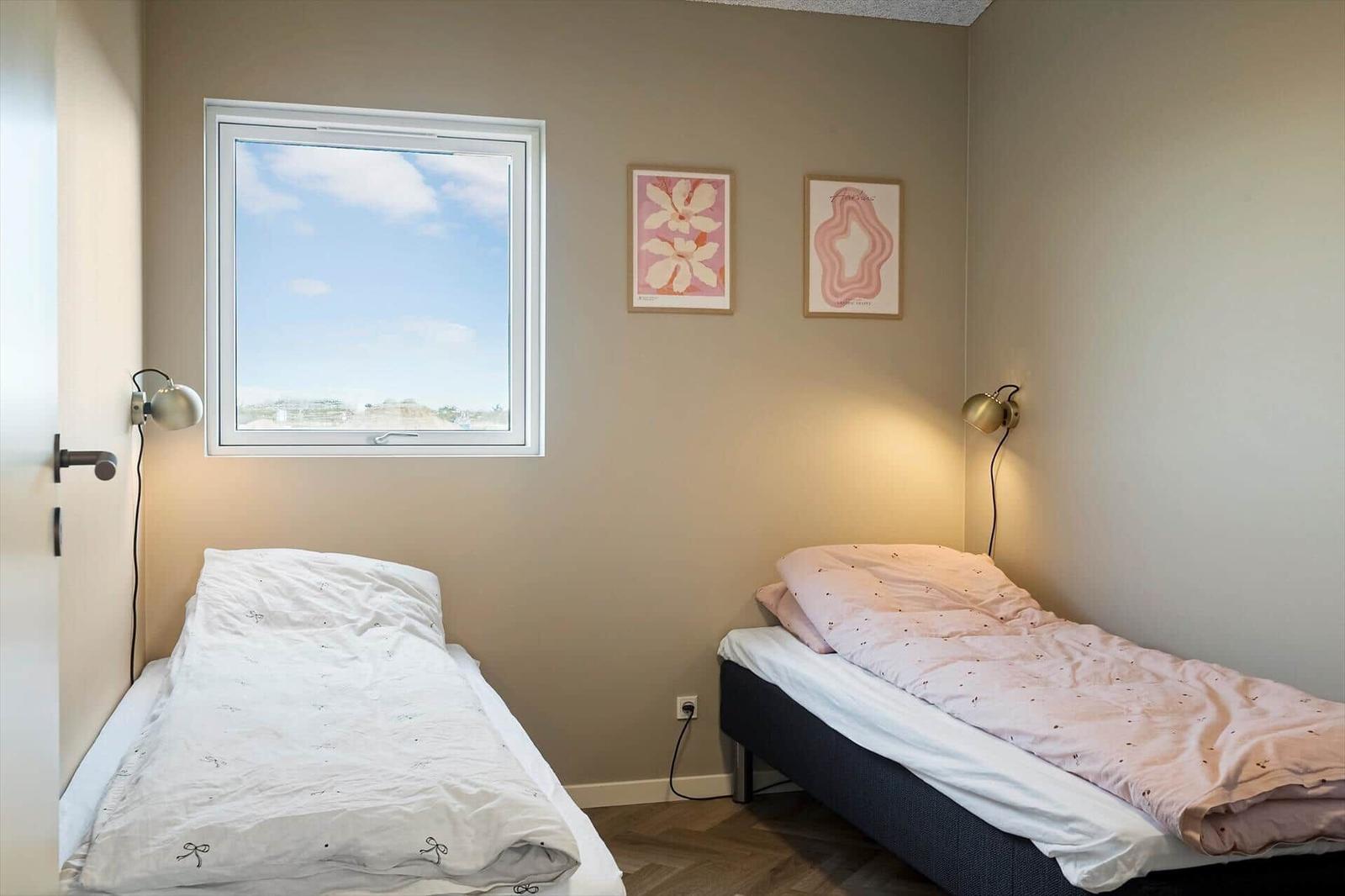 Zwei Betten mit Bettwäsche, Fenster und Wandbilder.