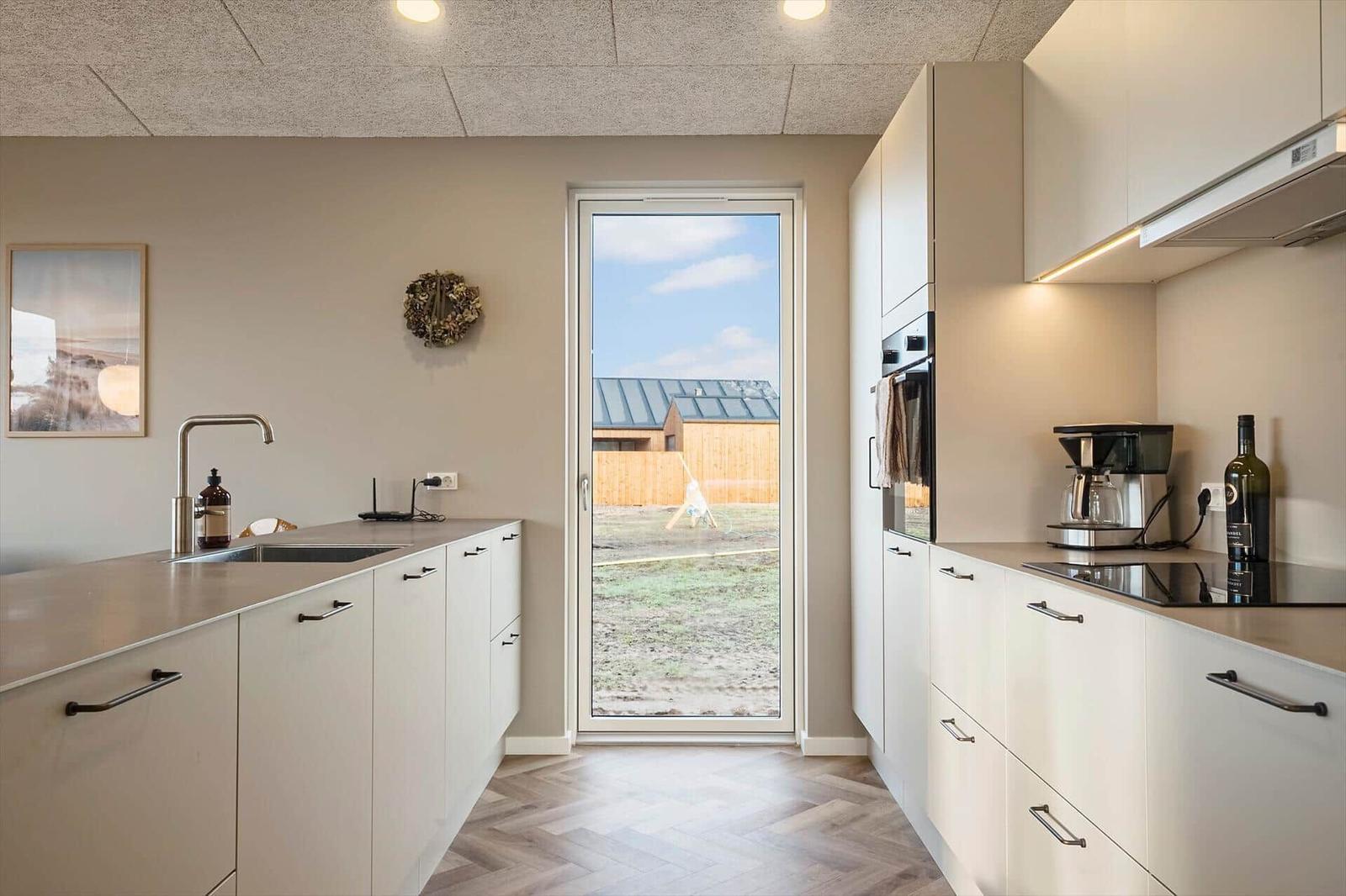 Moderne Küche mit Blick auf Garten und Nachbarhaus.