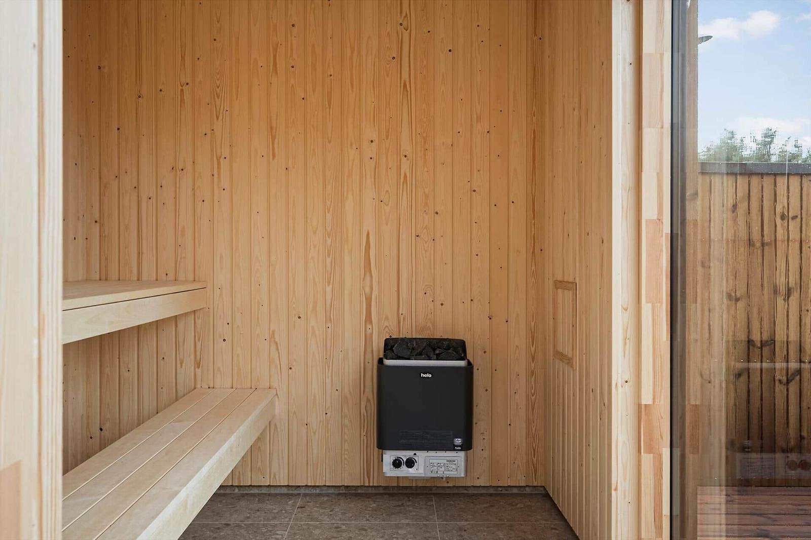 Sauna mit Holzwand und Sitzbank sowie Heizgerät.