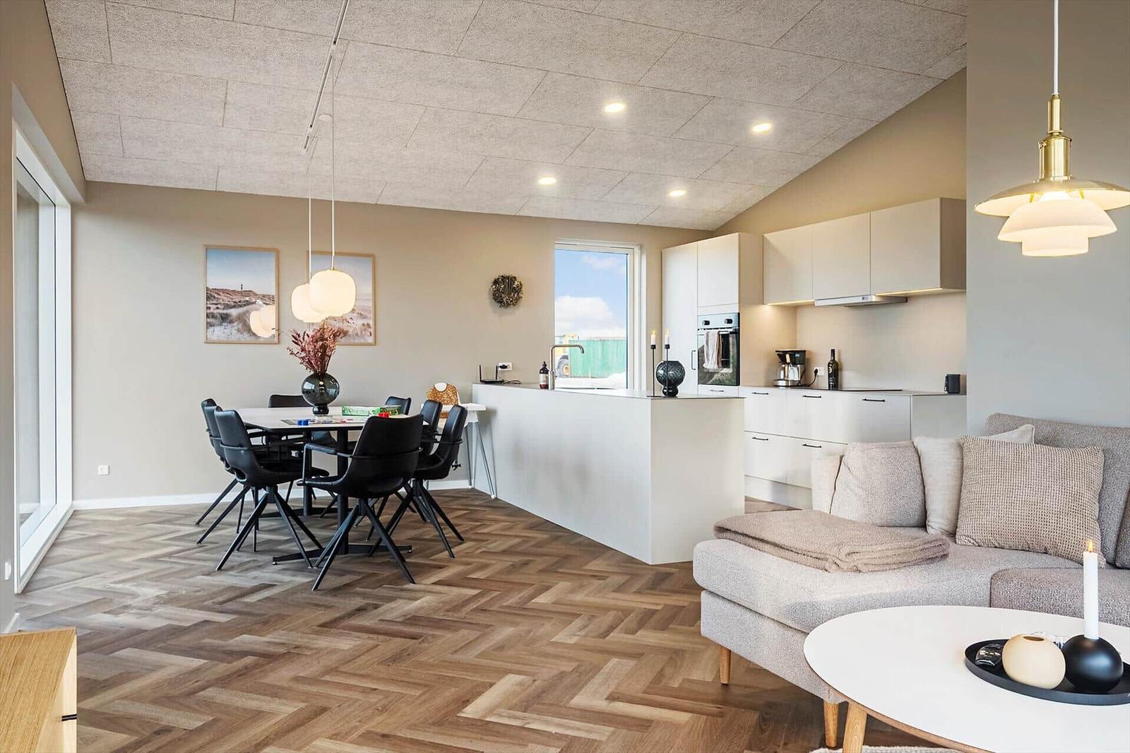 Wohn- und Essbereich mit Kücheninsel, Esstisch und Sofa.