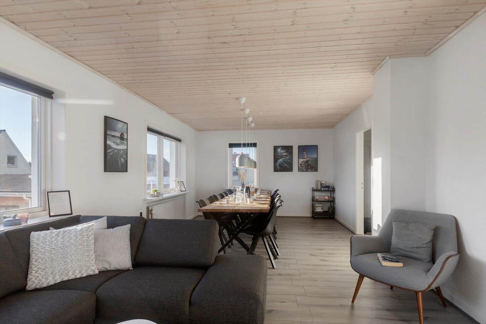 Living and dining area with sofa, chair, table, and windows.