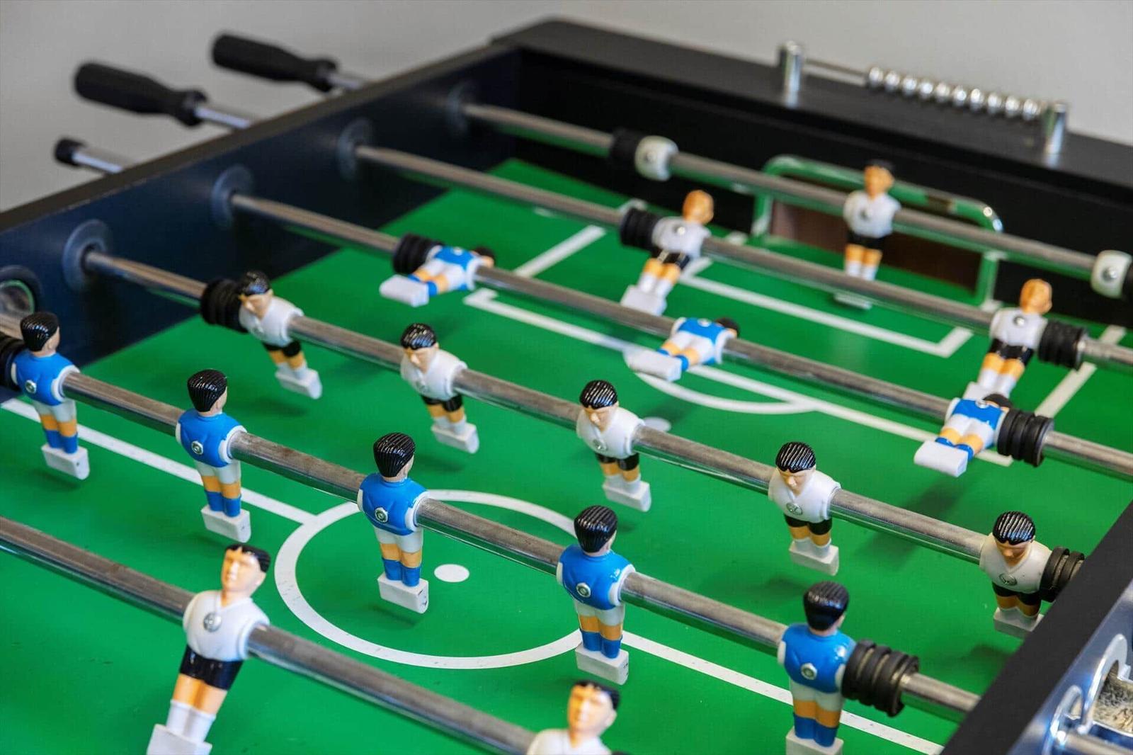 Foosball table with blue and white players on green field.