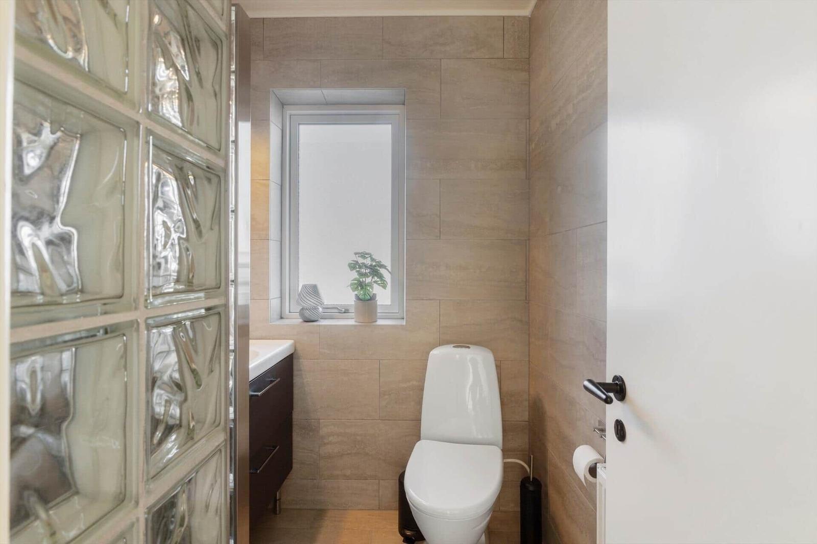 Bathroom with toilet, window, and glass block wall