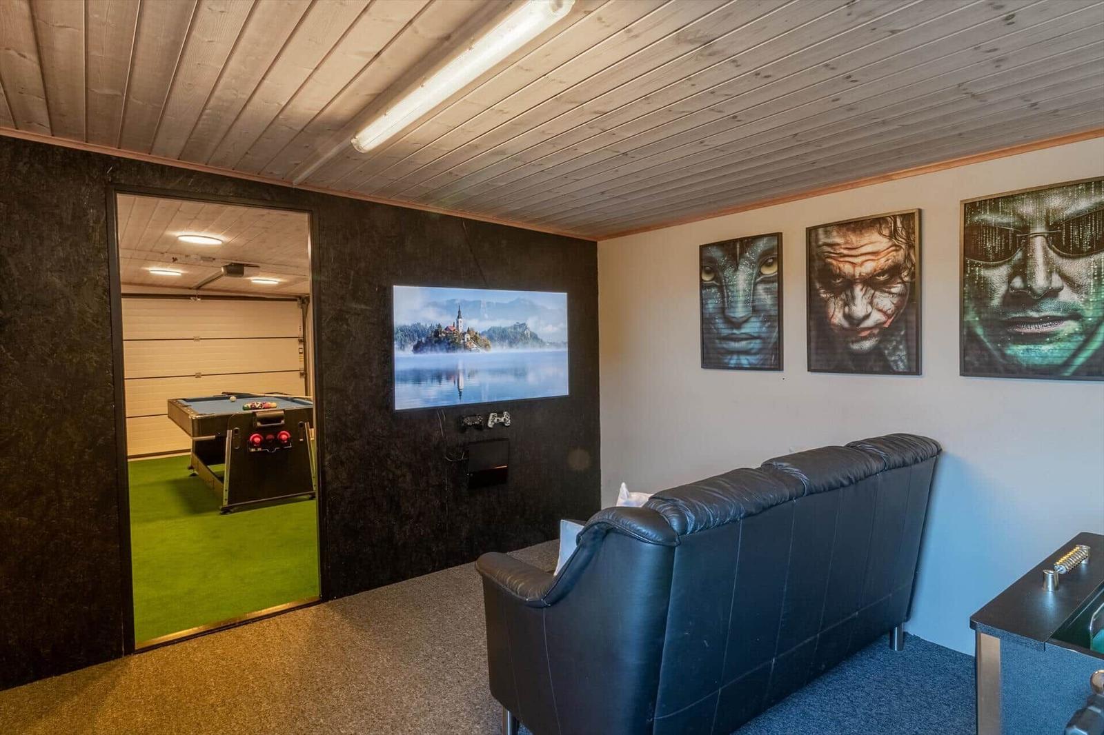 Living room with sofa, TV, and wall art. Passage to room with pool table.