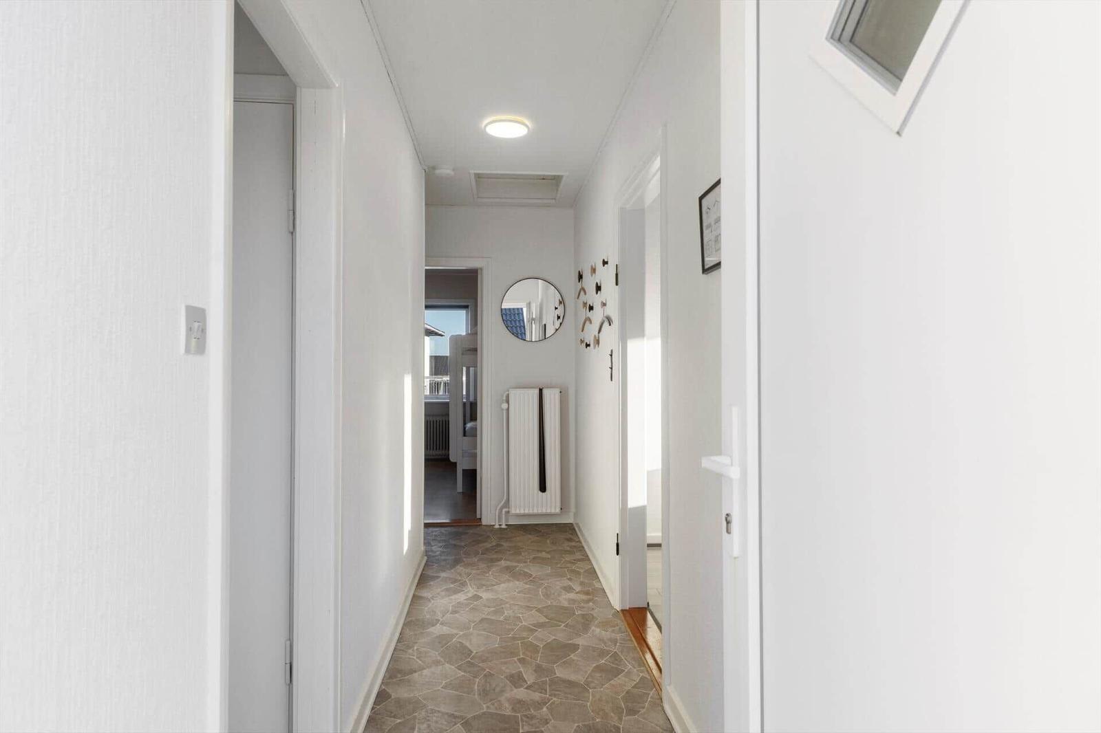 Hallway with stone floor, mirror, and radiator on the wall.