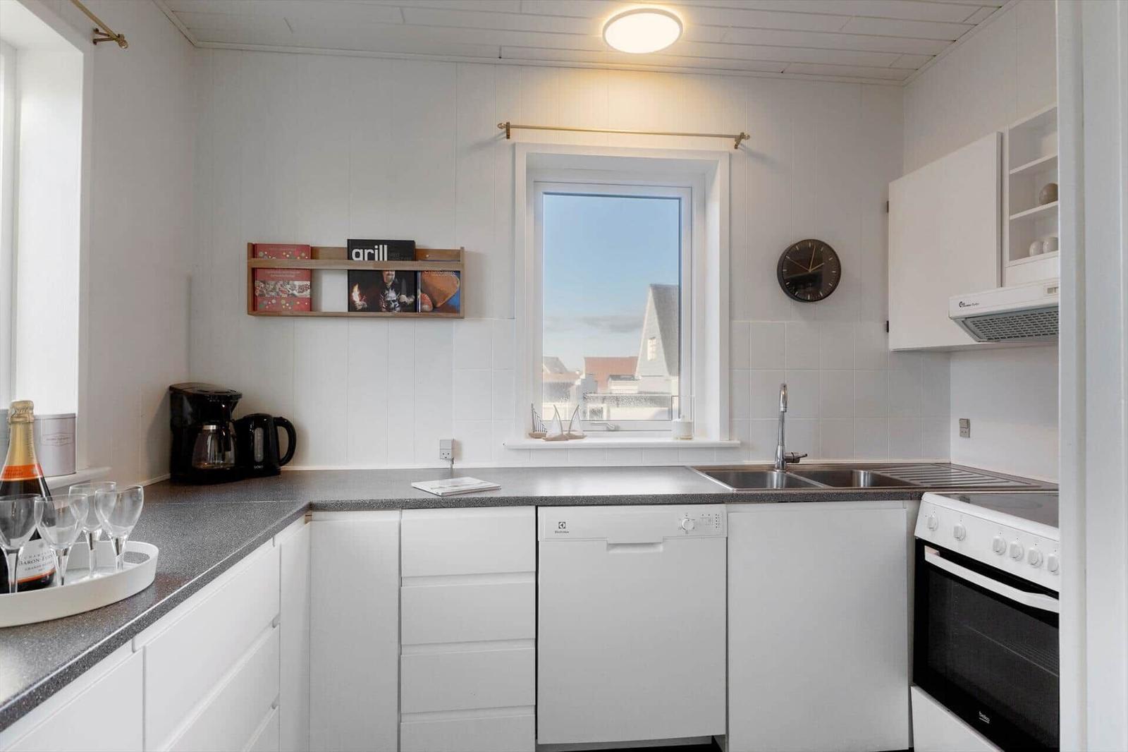 Kitchen with countertop, sink, stove, and window.