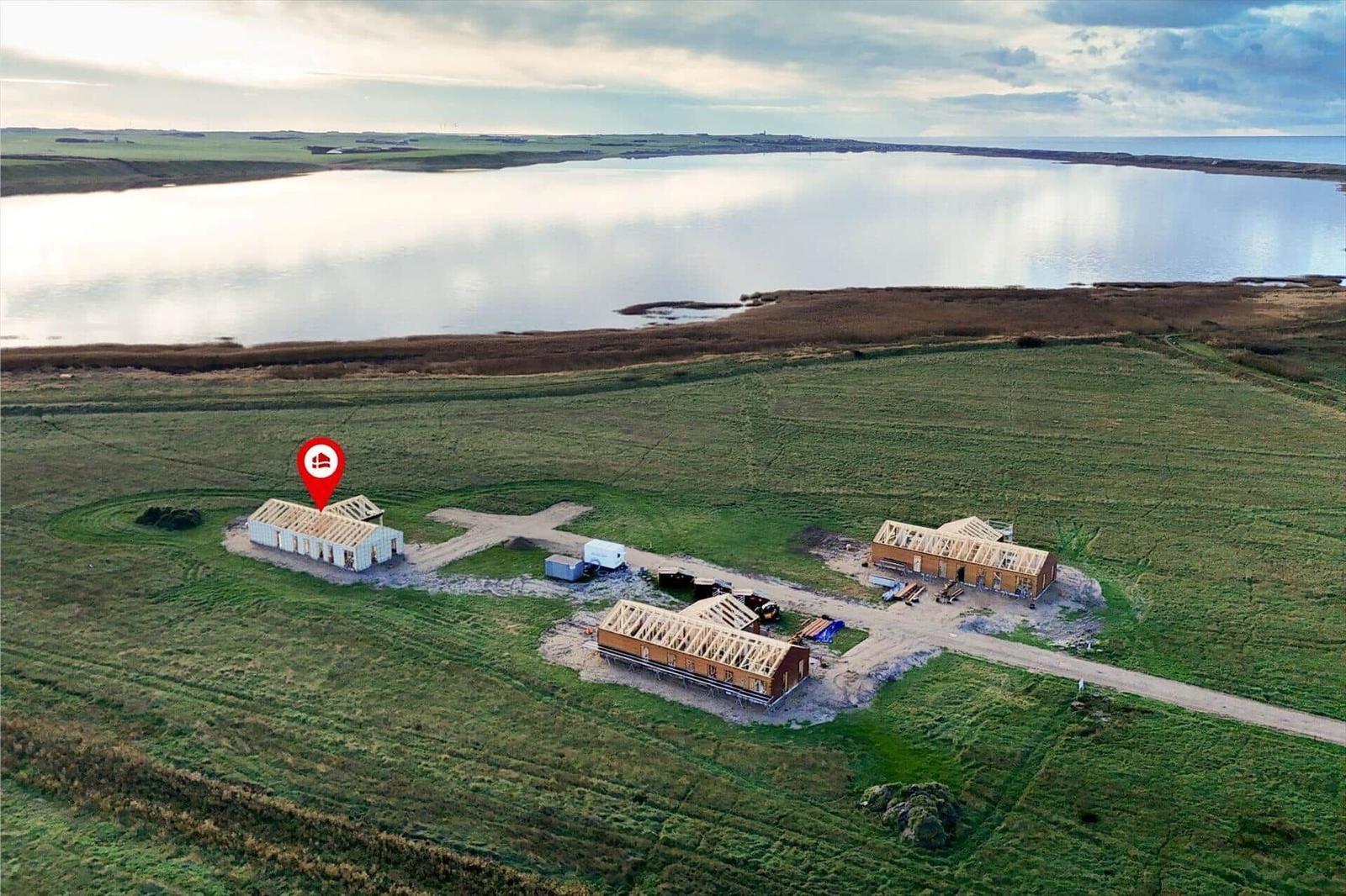 Drei Häuser auf einer grünen Wiese neben einem See