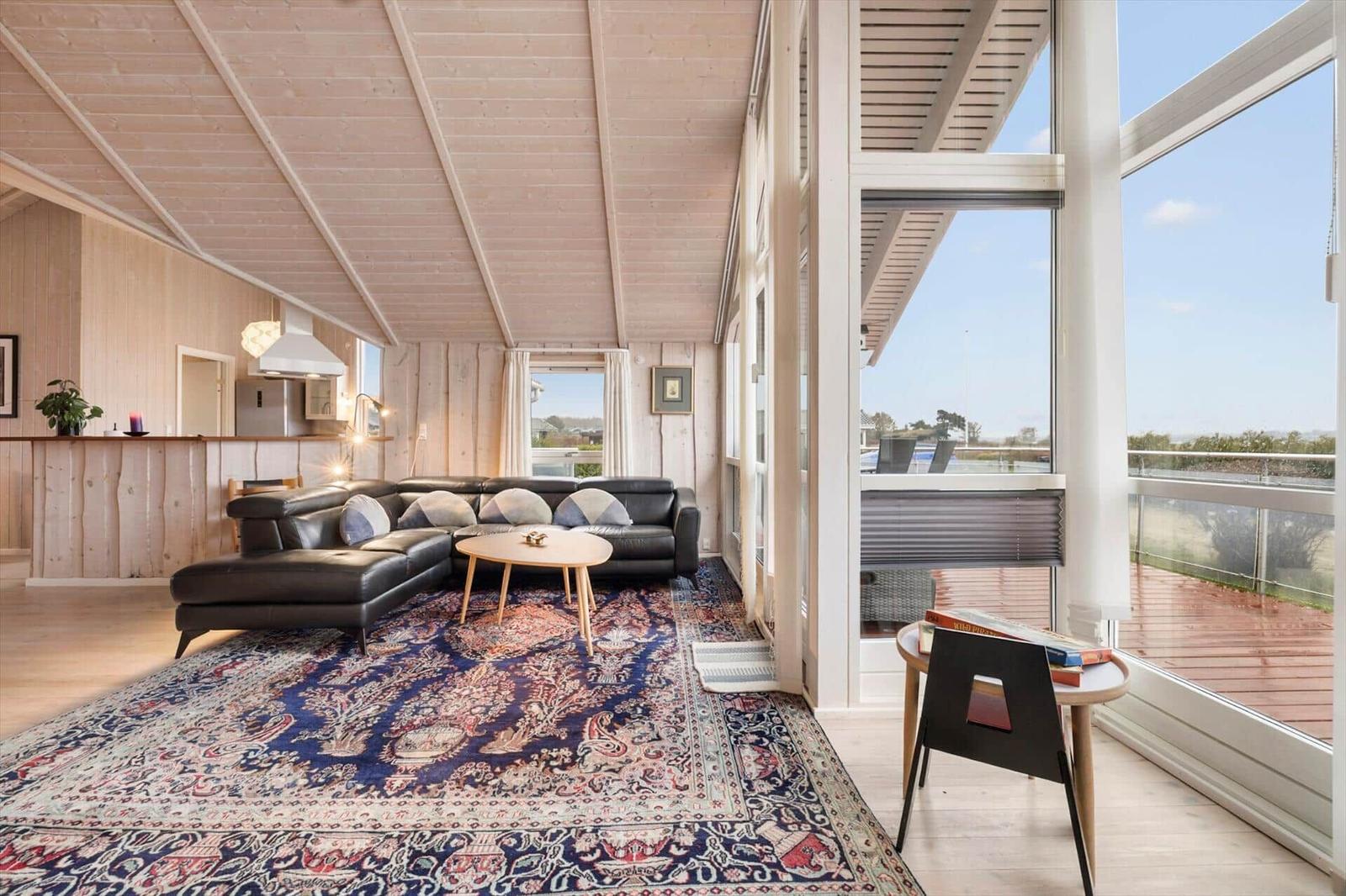 Living area with sofa, rug, and large window to terrace.