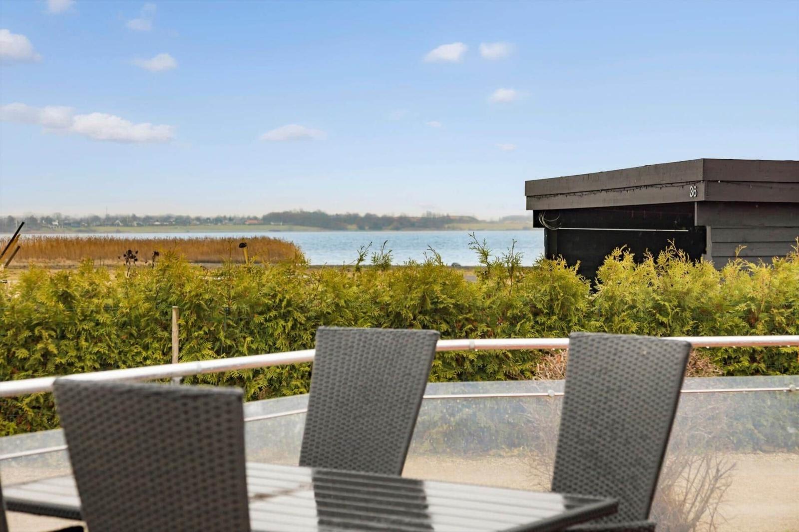 Terrace with seating and view of water and greenery.