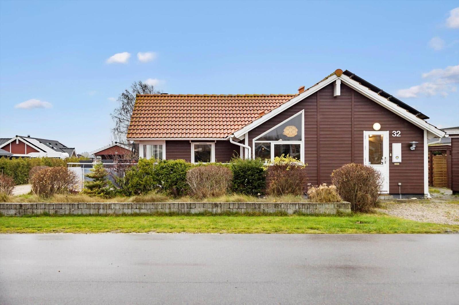 A brown house with a red roof and white door on the street.